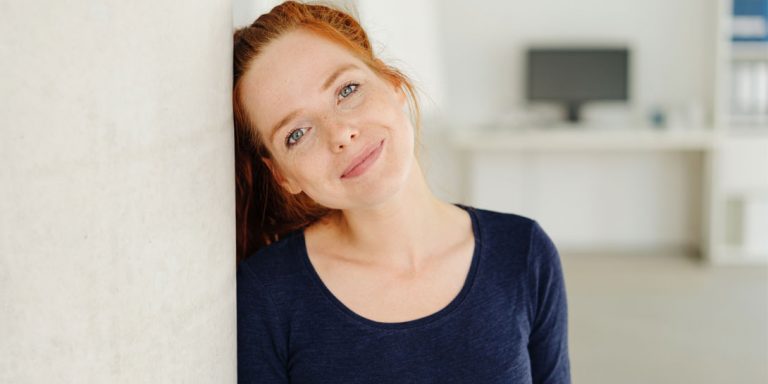 En rødhåret kvinde står og smiler