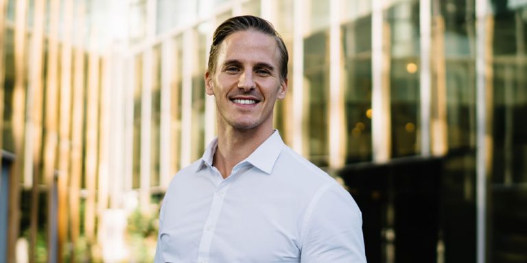 En mand i skjorte står foran en bygning