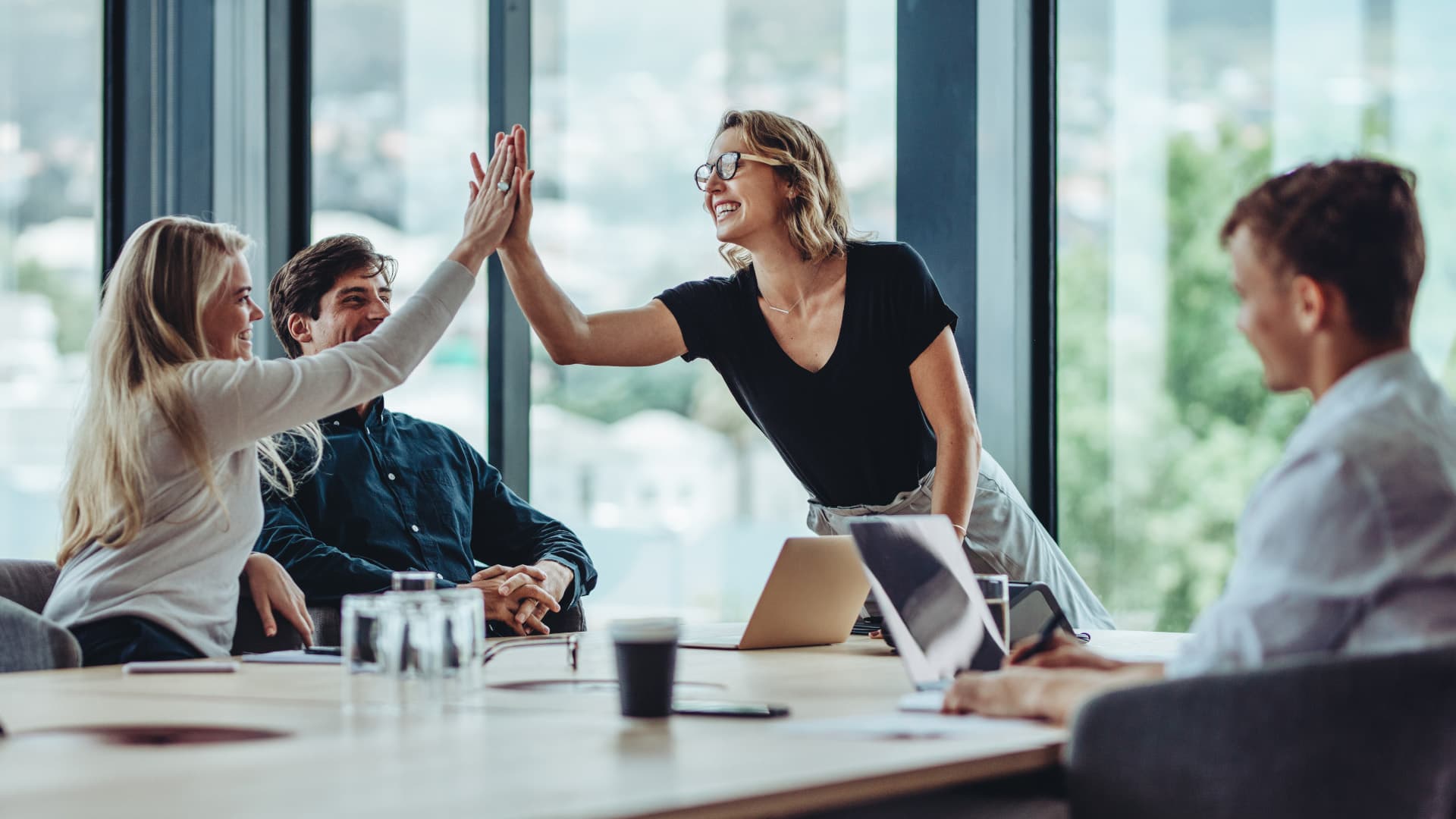 En gruppe mennesker holder møde og to kvinder giver hinanden en high-five