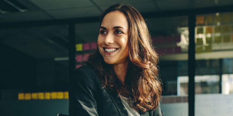 En kvinde står og smiler foran post-it notes